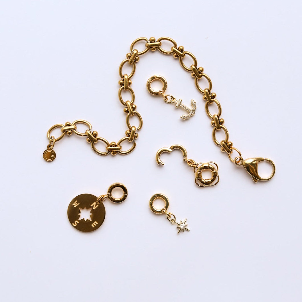 Gold bracelet with various charms on a light background